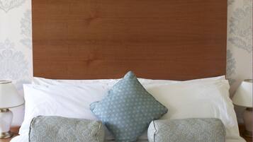A neatly made bed with a wooden headboard, two patterned pillows, and a white comforter.