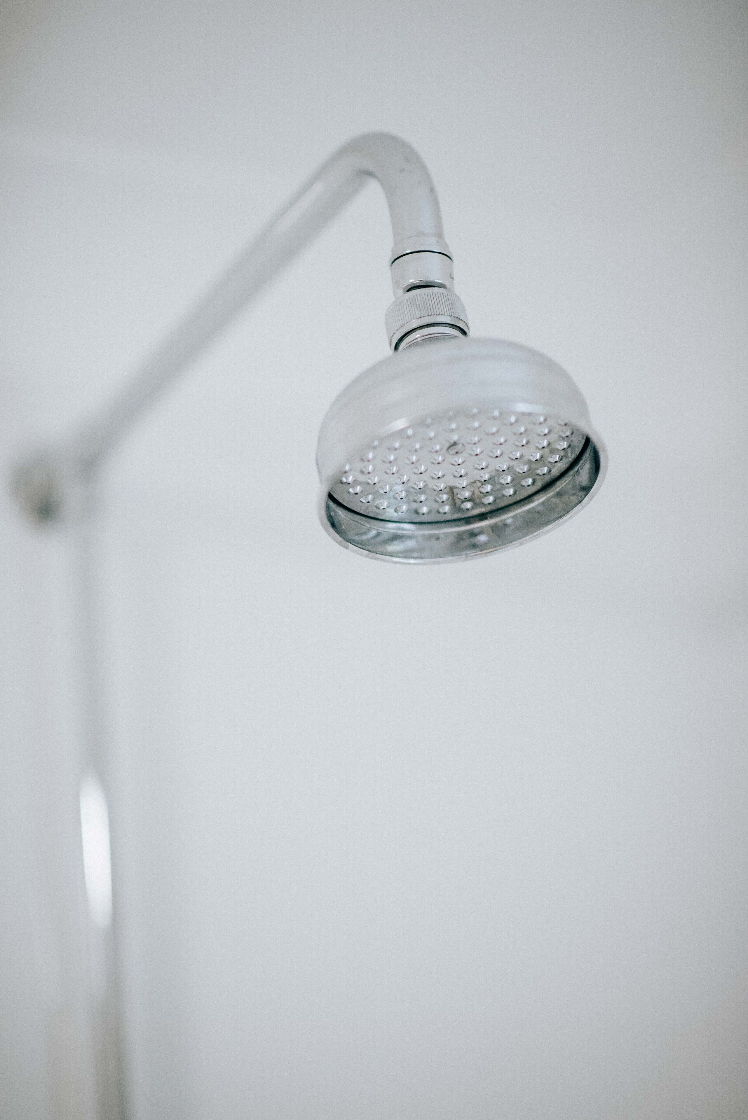 A showerhead with a curved handle and a round, transparent water cover.