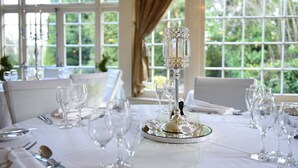Een gedekte tafel voor een formeel diner, met een kristallen kaarsdecoratie, glazen en een witte tafelkleed.