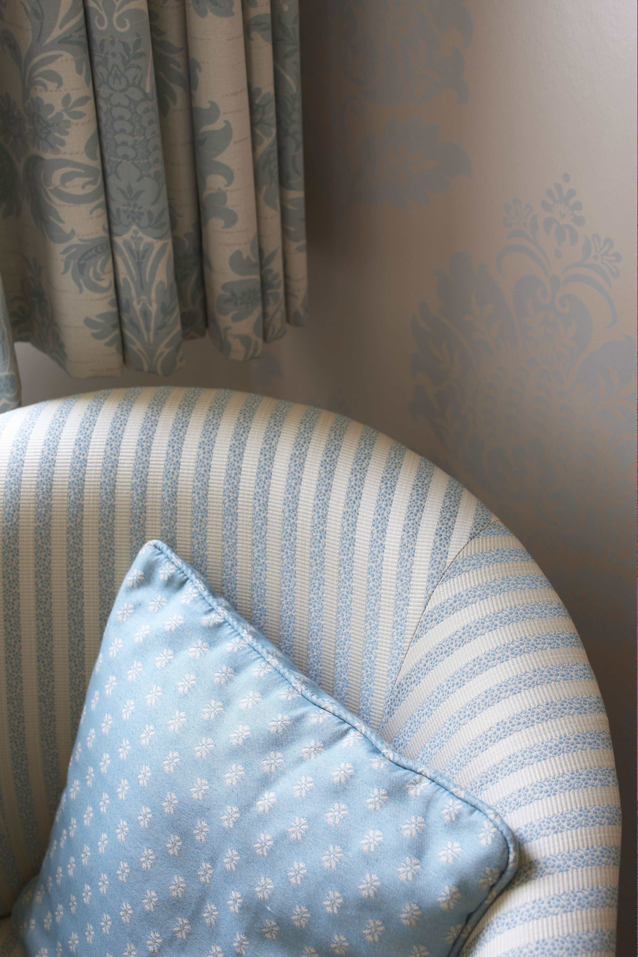 Una silla con estampado a rayas y un cojín azul con diseño floral.