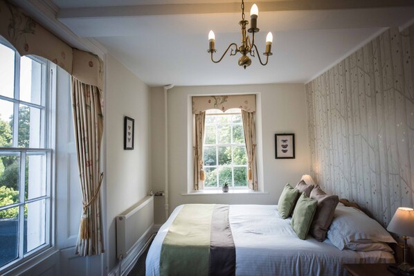A bedroom with a large bed, a window with curtains, a radiator, and a chandelier. - Flackley Ash Country House Hotel (Rye)