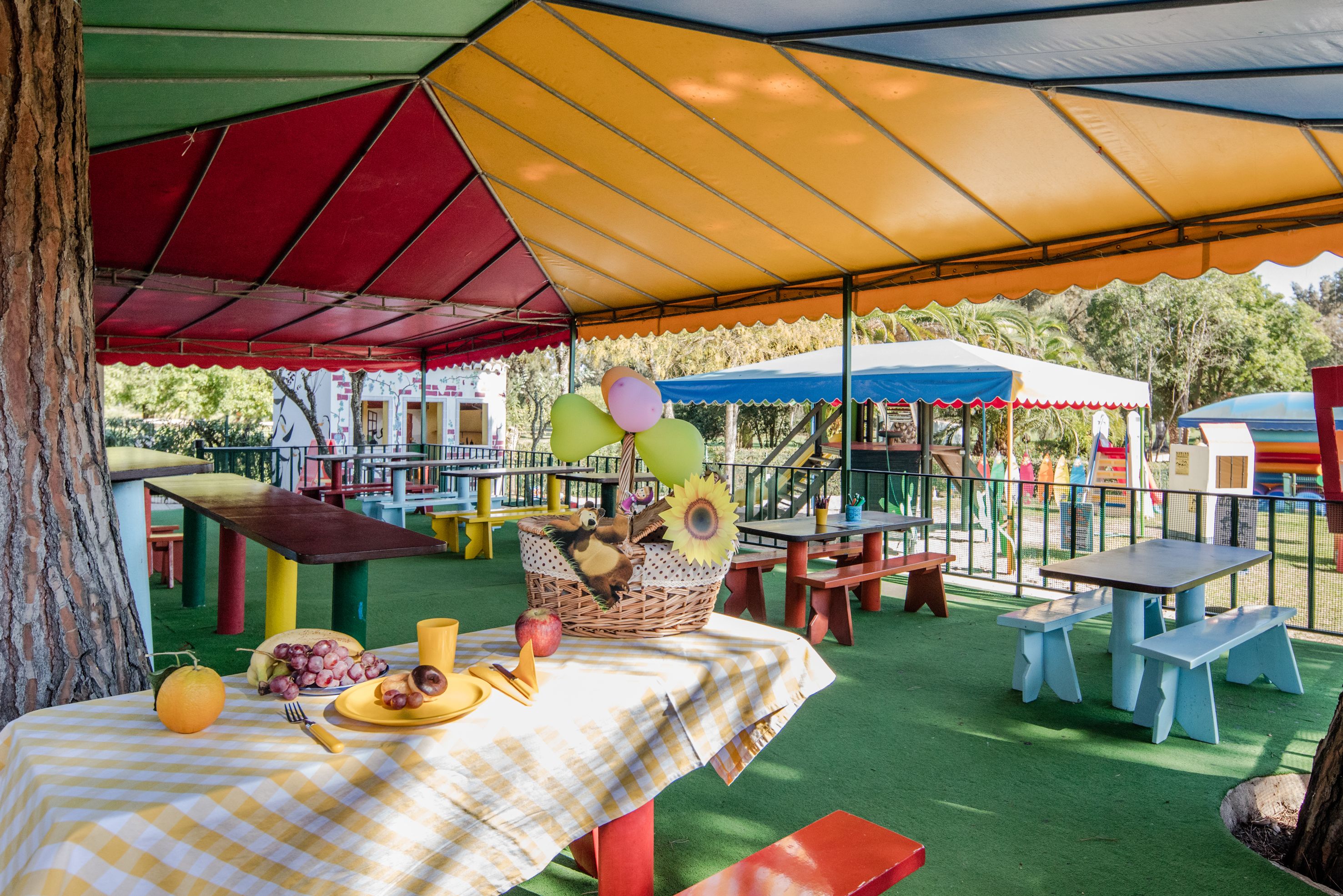 An outdoor dining area with picnic tables and benches, surrounded by colorful umbrellas.