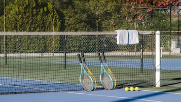 A tennis court with a net, two tennis rackets, and three tennis balls.