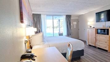 A hotel room with a bed, a desk with a telephone, a television, and a cabinet.