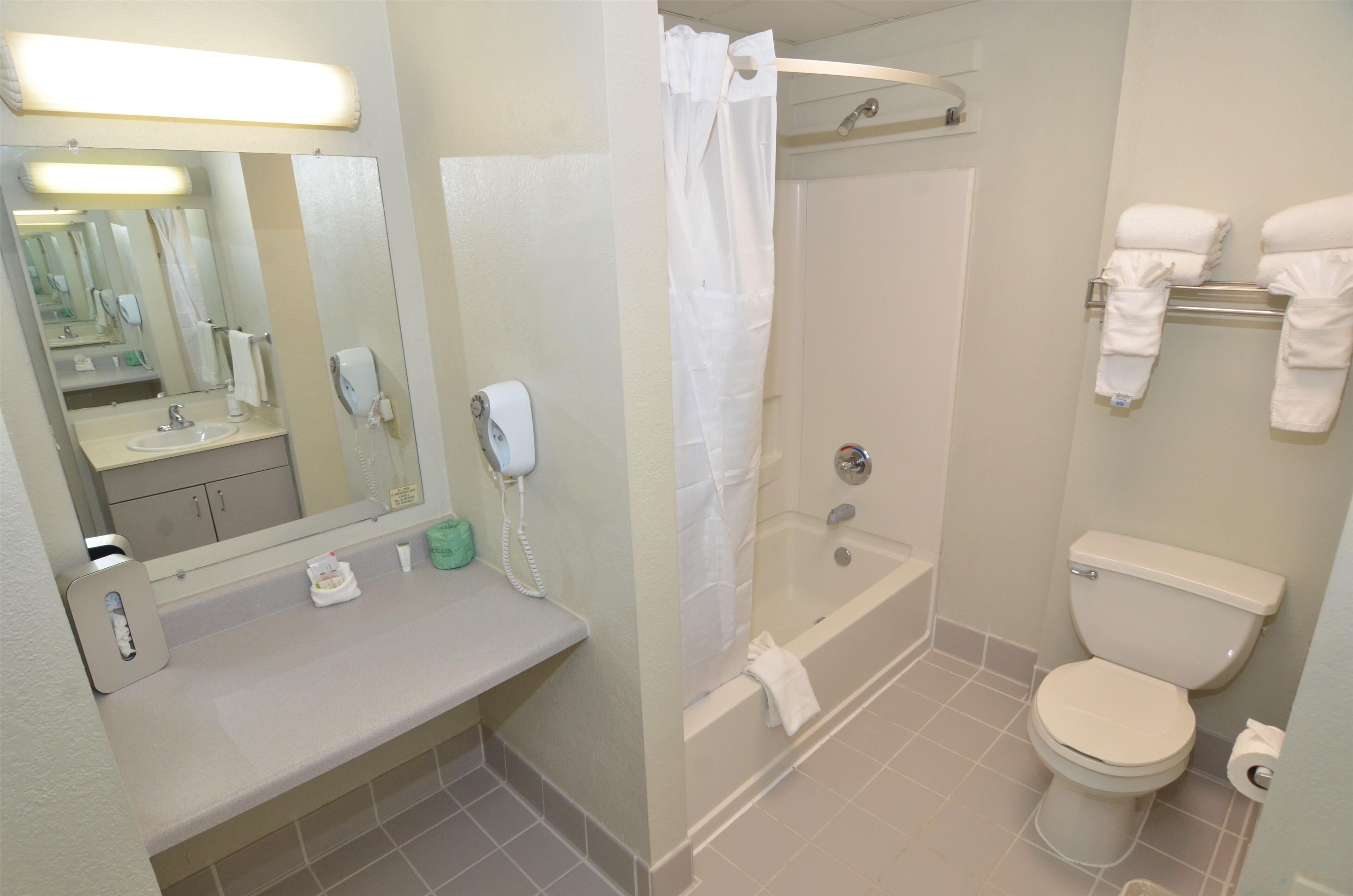Un baño con lavamanos, espejo, inodoro y bañera.