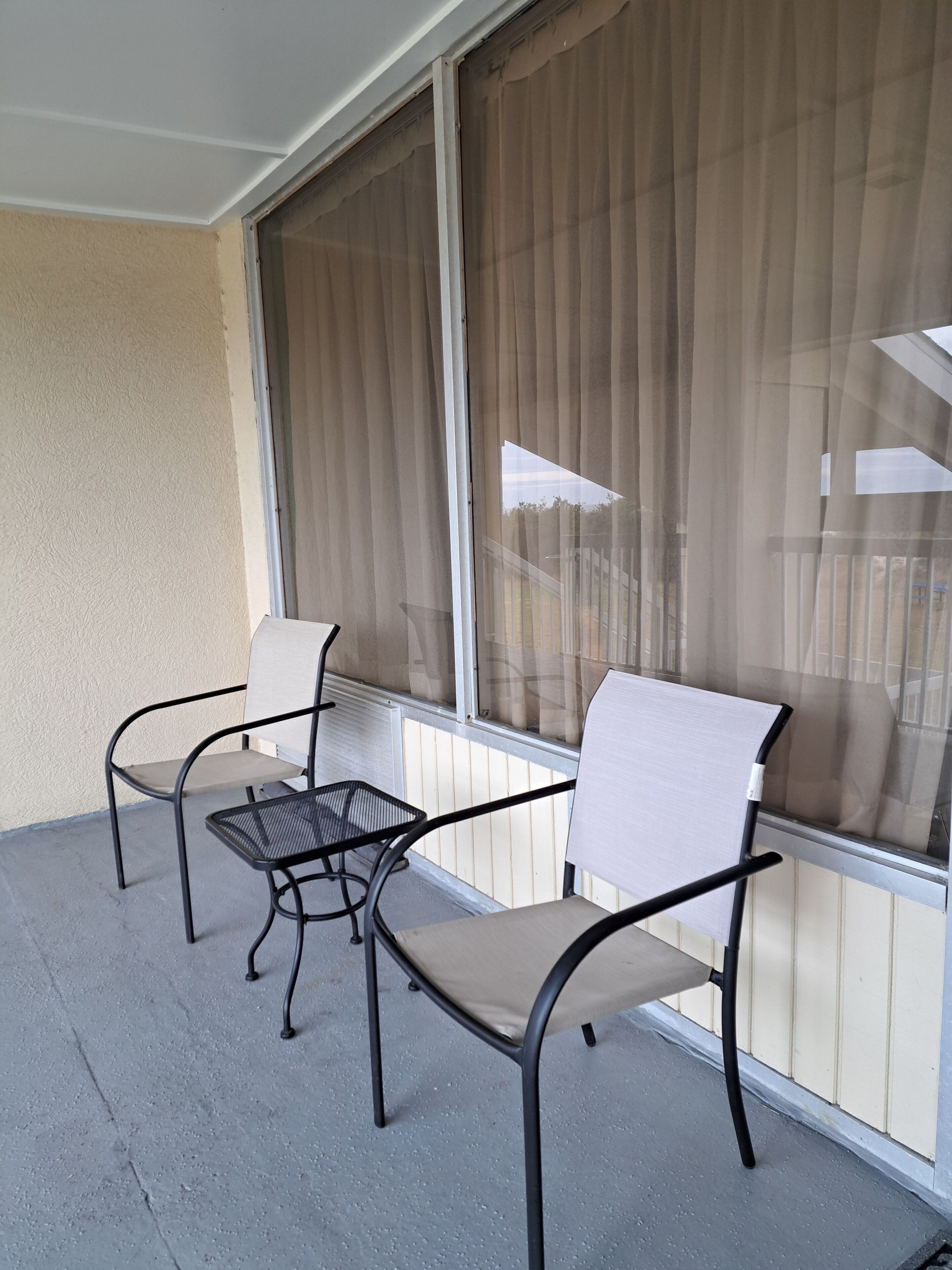 A balcony with two chairs and a small table.