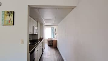 A narrow hallway with a kitchen area on the left, featuring cabinets and a countertop.