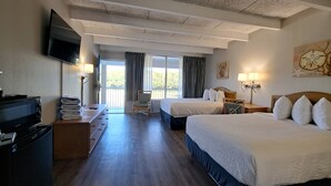 A hotel room with two beds, a desk with a TV, and a view of the outdoors. - Days Inn & Suites by Wyndham Jekyll Island (Jekyll Island)