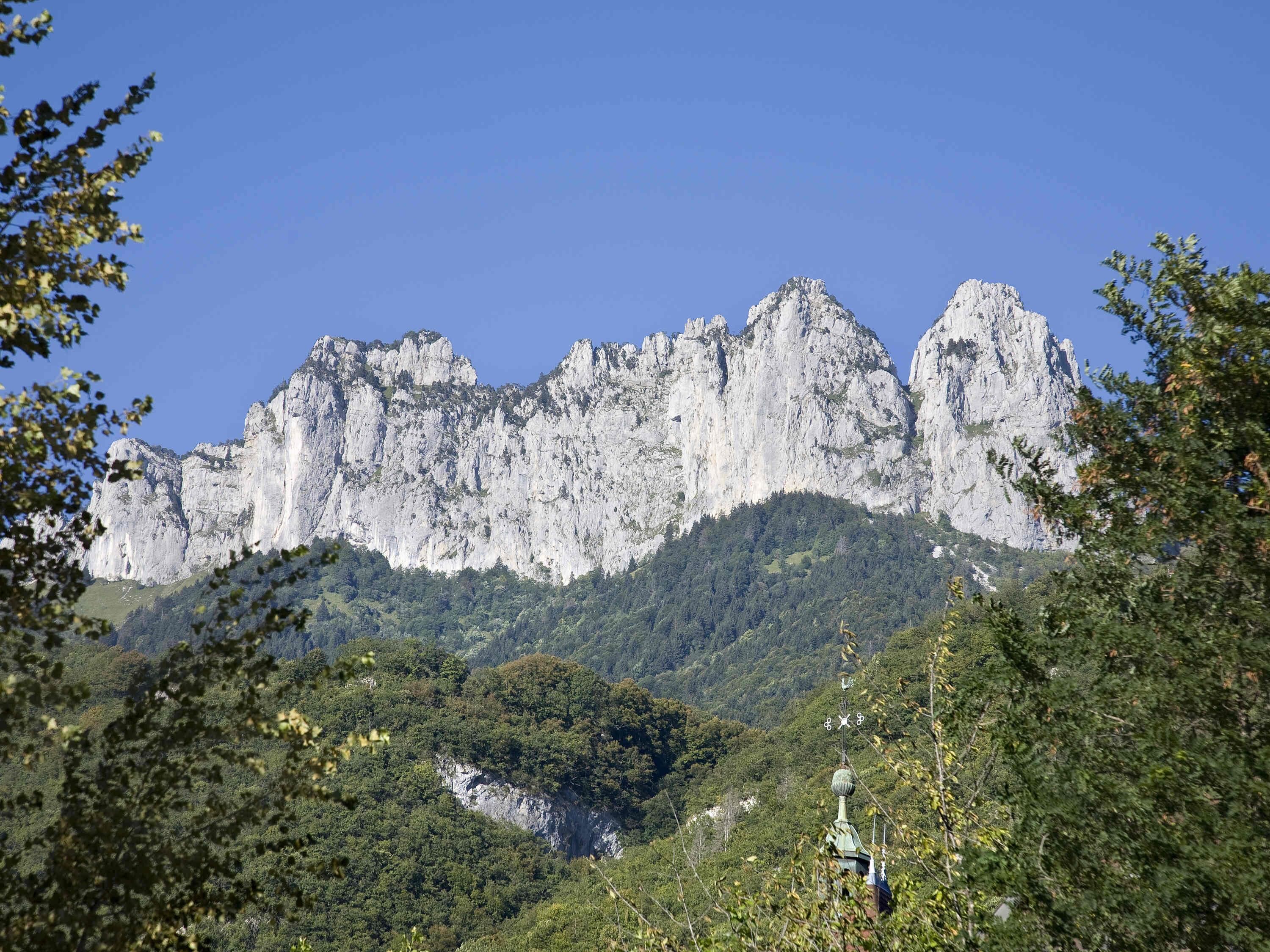 A mountainous landscape with rocky cliffs and dense forest.