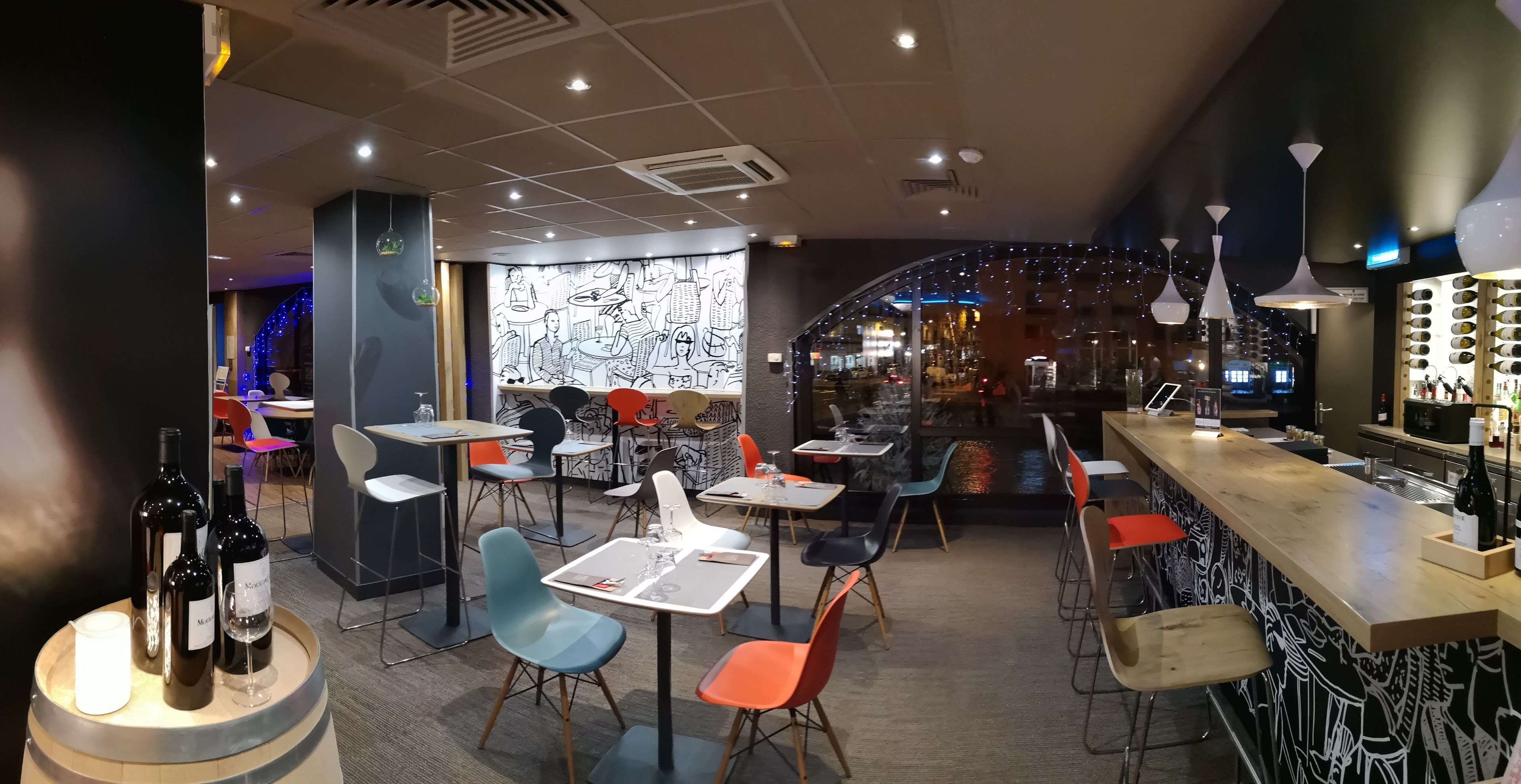A modern restaurant interior with tables, chairs, and a bar area.