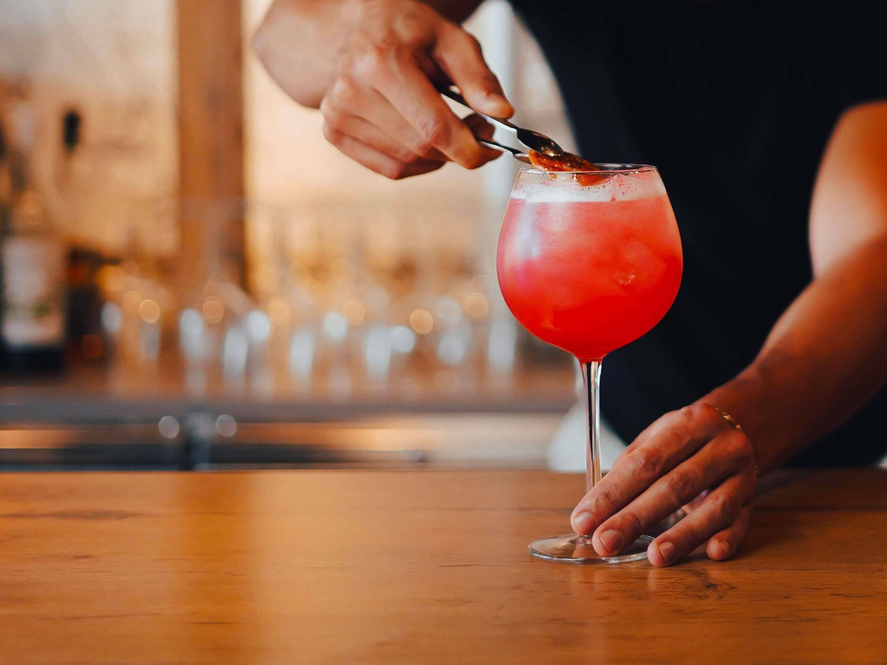 A person pouring a red drink into a glass.