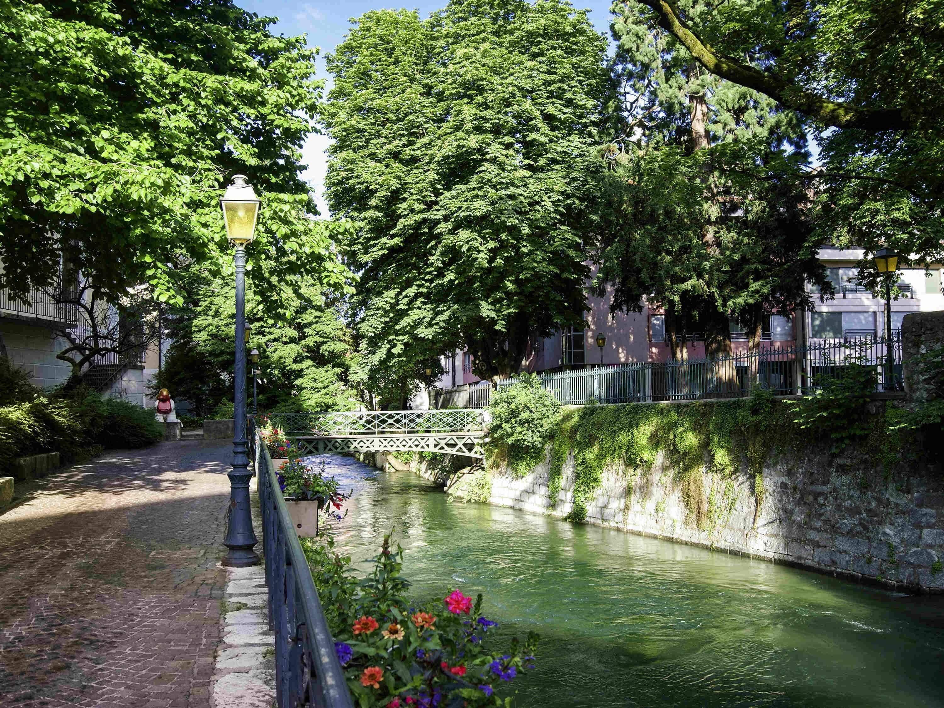 Un canal con un puente, rodeado de árboles y edificios.