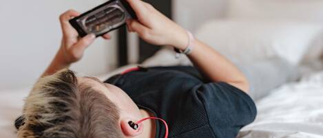 A person lying on a bed with a smartphone in hand.