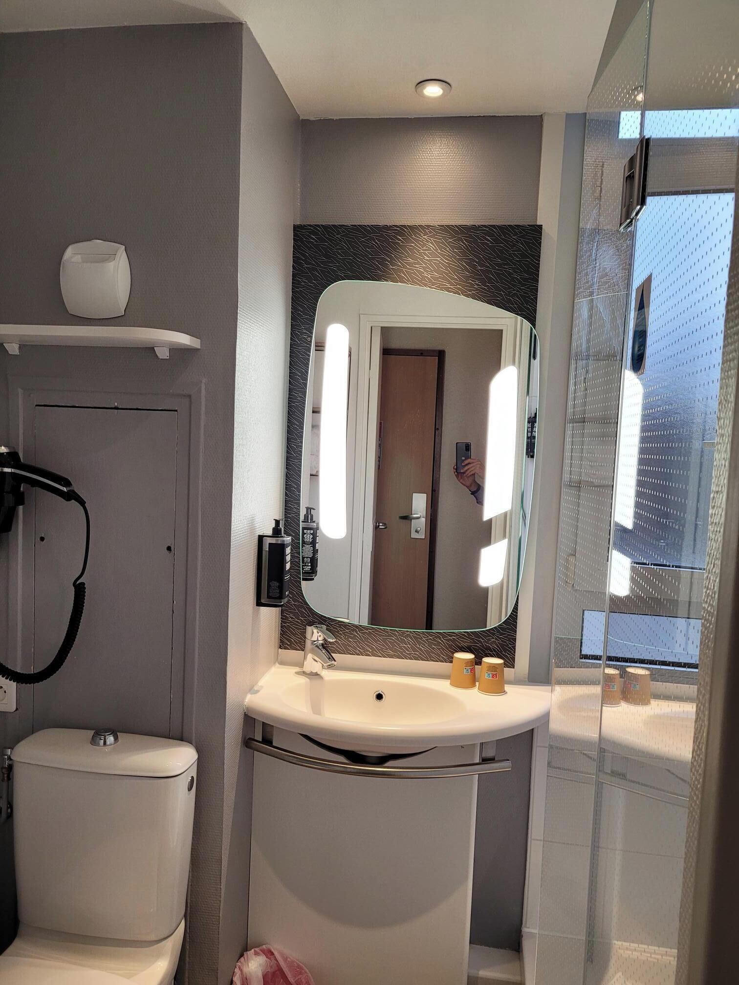 A modern bathroom with a toilet, sink, and mirror.