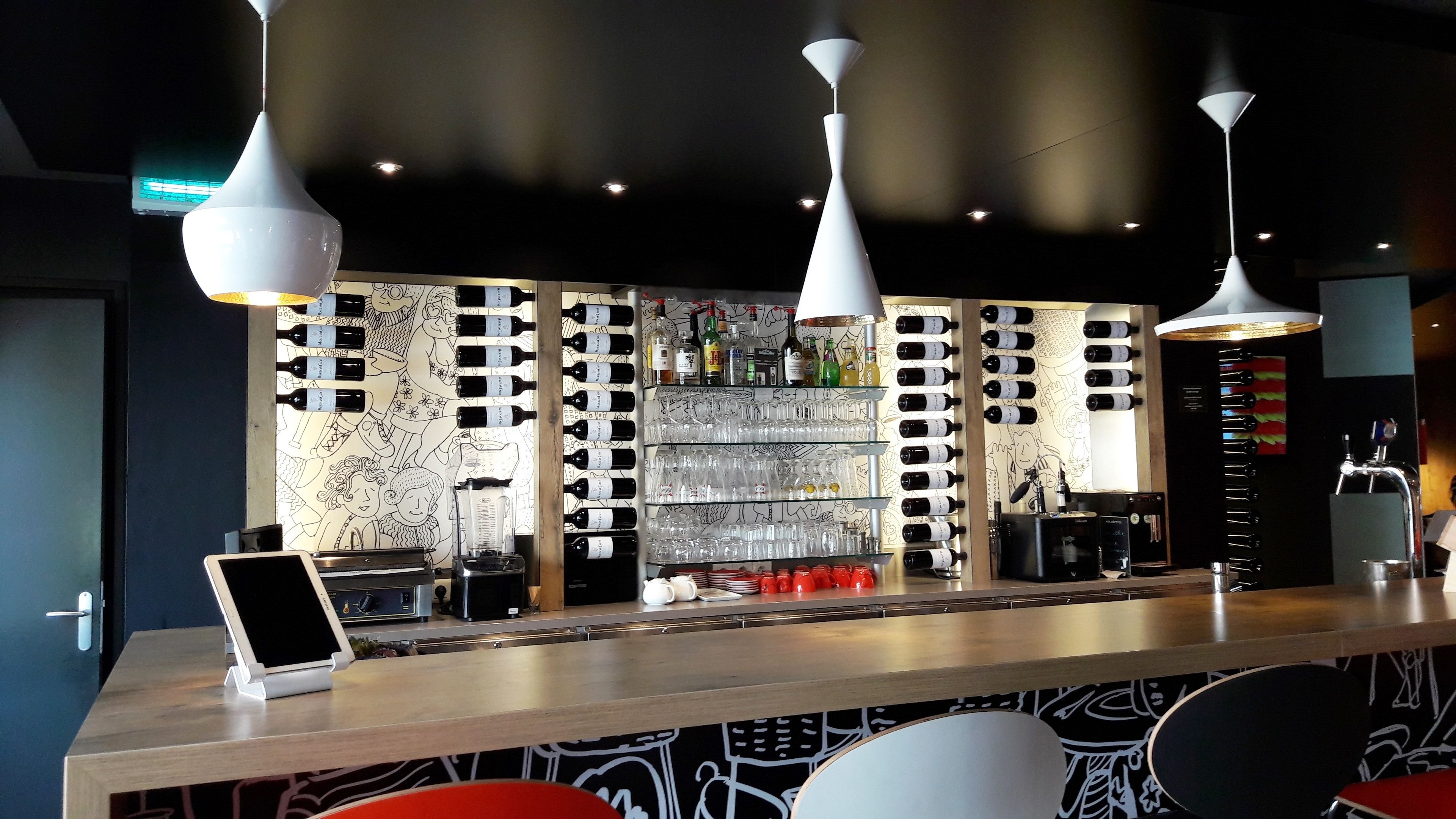 A bar area with a counter, wine bottles, glasses, and a coffee machine.