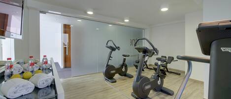 Un gimnasio moderno con equipo de ejercicio, toallas y botellas de agua sobre una encimera.