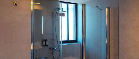 A modern bathroom with a glass-enclosed shower, a toilet, and a window providing natural light.