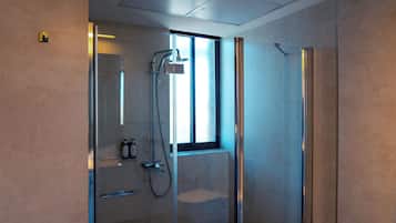 A modern bathroom with a glass-enclosed shower, a toilet, and a window providing natural light.