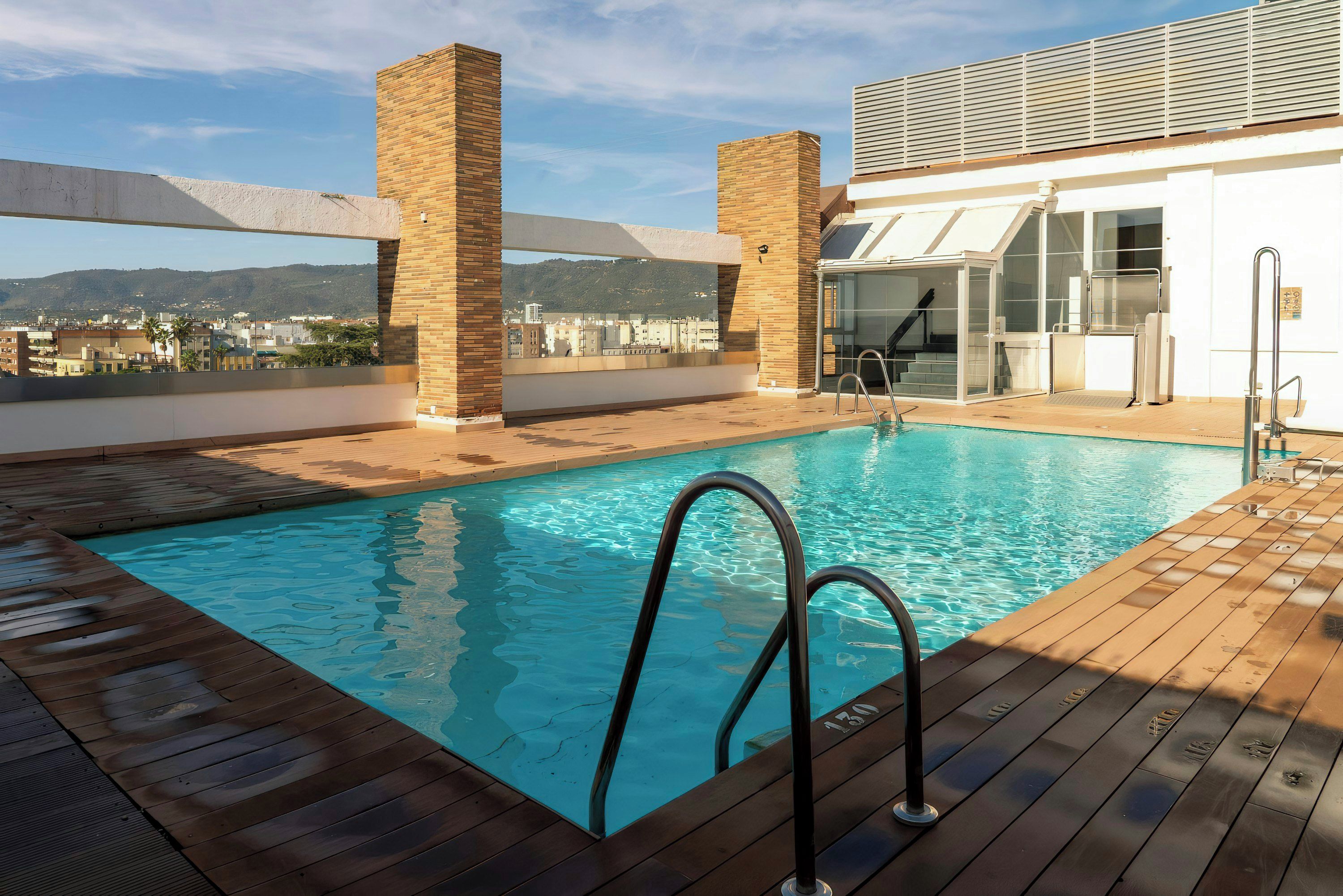 Una piscina en la azotea con vistas despejadas del paisaje urbano al fondo.