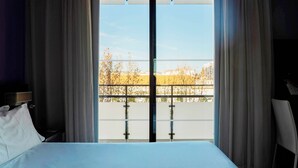 Une chambre d’hôtel avec un lit, une table de chevet et une vue sur un balcon doté d’une balustrade.