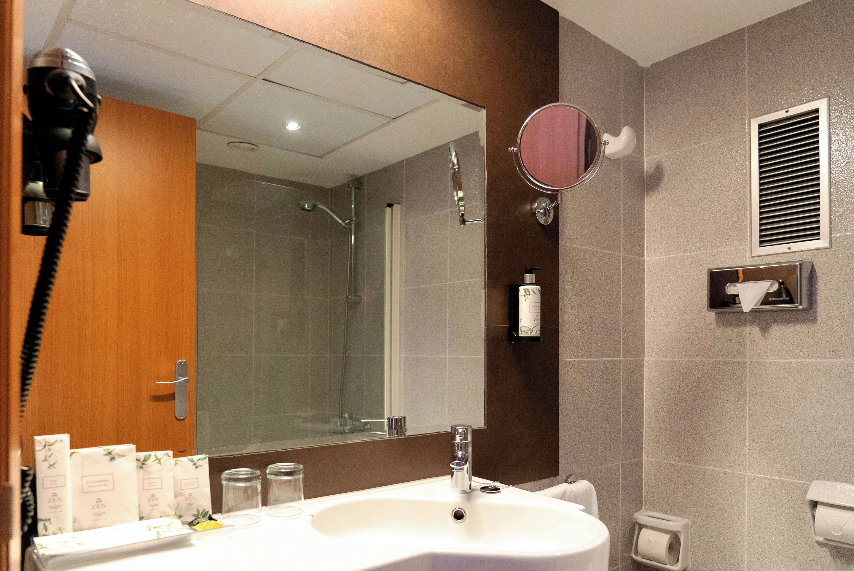 Un baño moderno con un espejo grande, un lavamanos, una ducha y un inodoro.