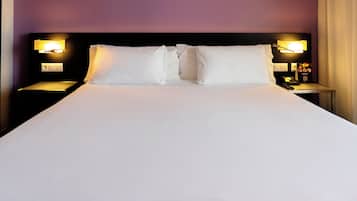 Una cama bien hecha con sábanas blancas y dos almohadas, flanqueada por mesitas de noche con lámparas y un pequeño reloj.