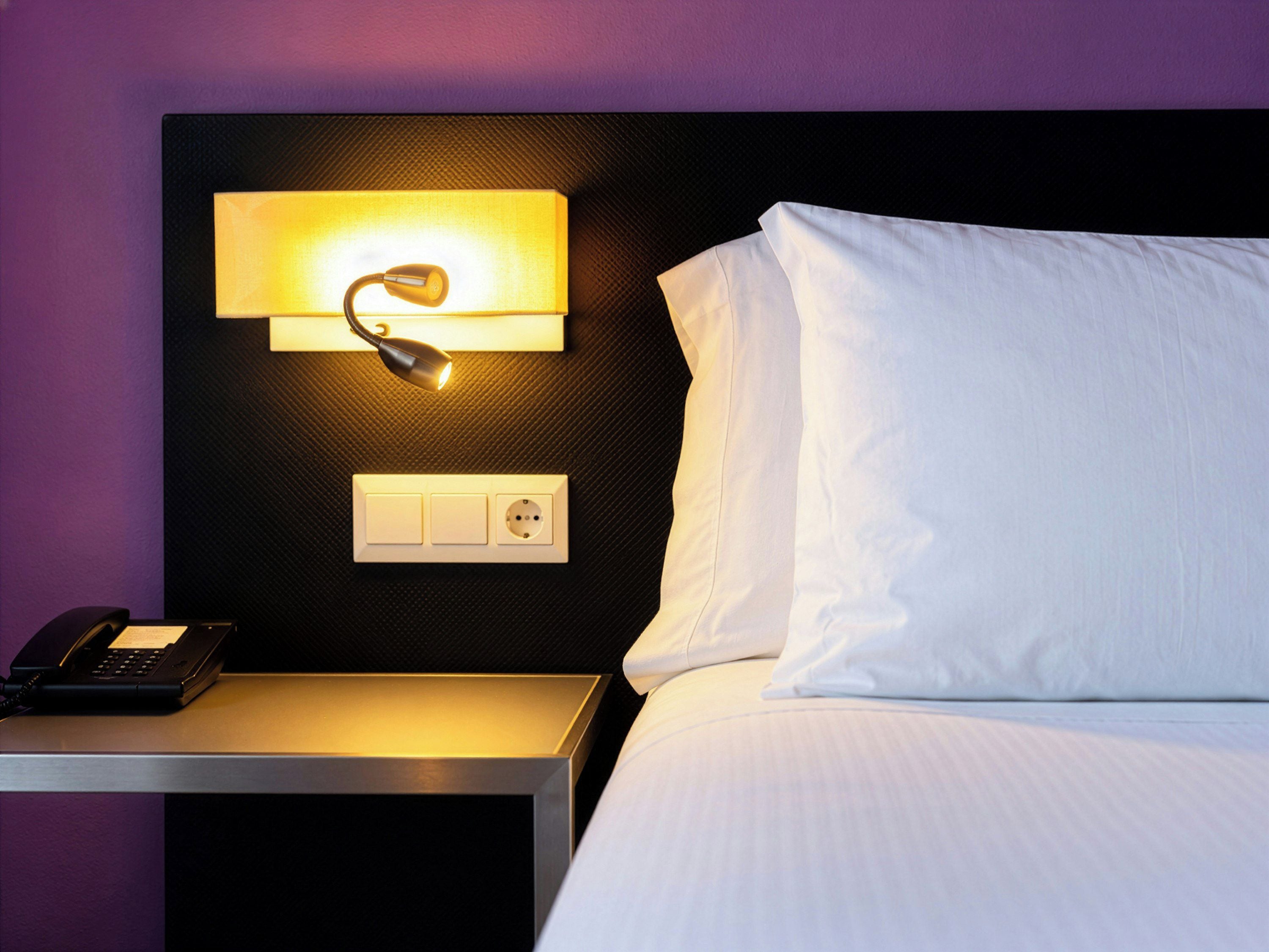 Une chambre d’hôtel avec un lit, une table de chevet, une lampe et un téléphone.