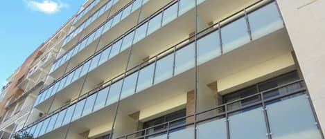 Un edificio de varios pisos con un diseño arquitectónico moderno, con amplias ventanas de vidrio y balcones.