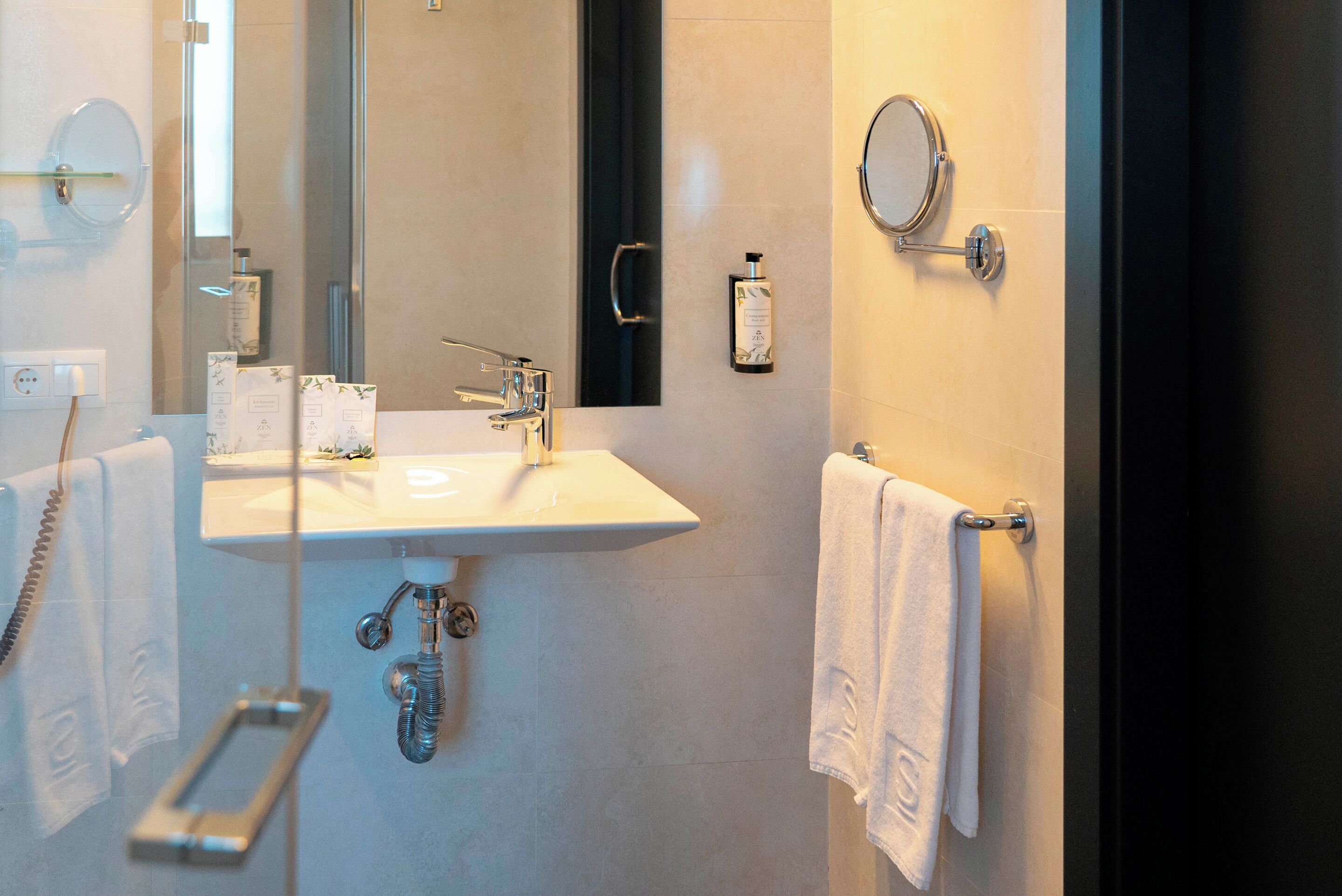 Un baño moderno con un lavamanos grande, un espejo, un perchero y un cabezal de ducha de mano.