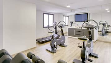 Un gimnasio moderno con equipo cardiovascular, televisión y zona de recepción.
