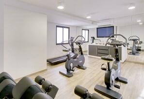Un centre de remise en forme moderne équipé de machines de cardio, d’un téléviseur et d’un espace d’accueil.