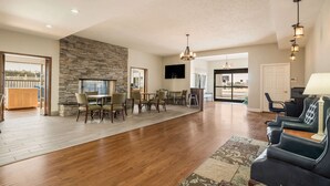 A spacious living area with a stone fireplace, wooden flooring, and a dining set. - Quality Inn Tulsa Central (Tulsa)