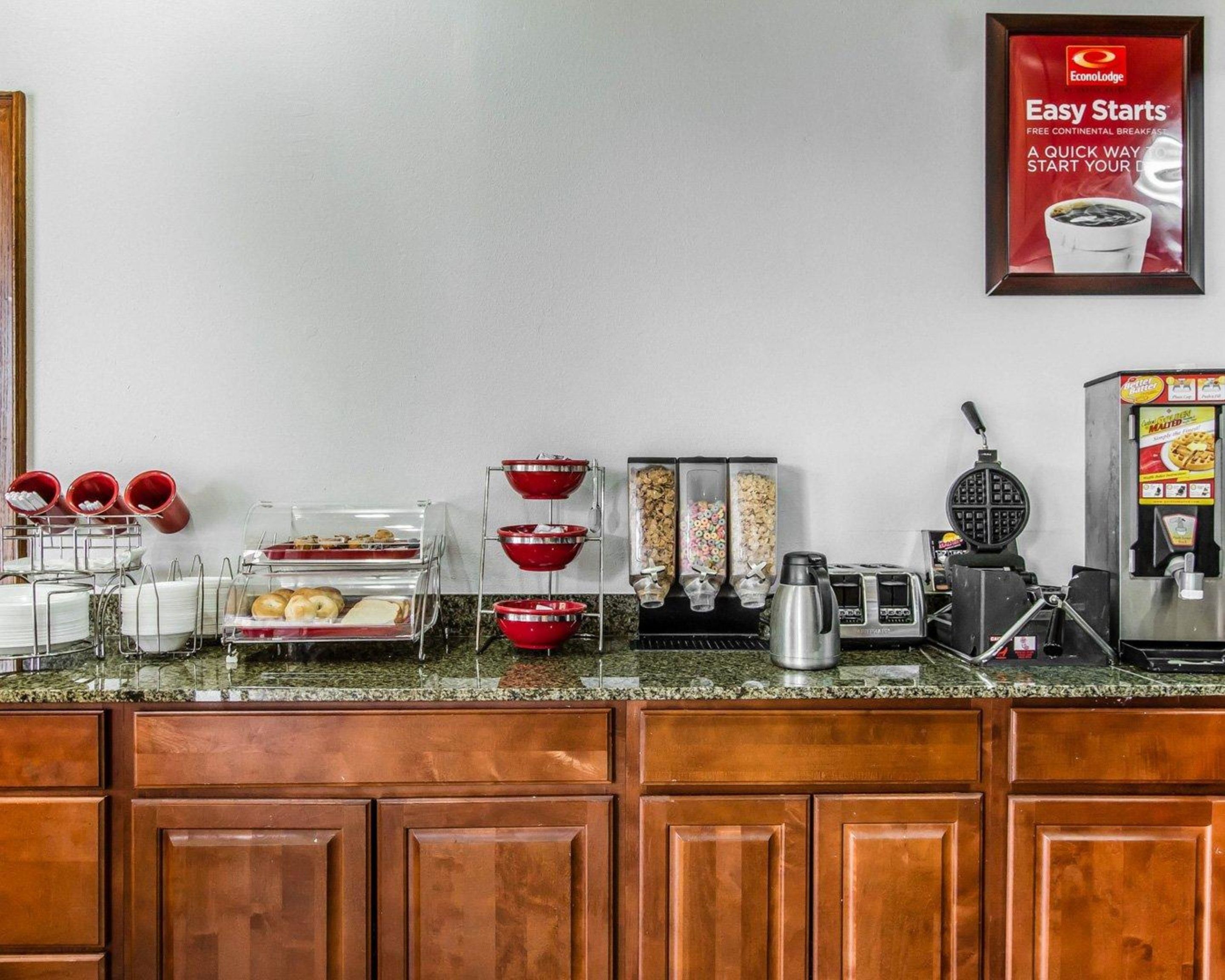 A breakfast bar with various food items and a waffle maker.