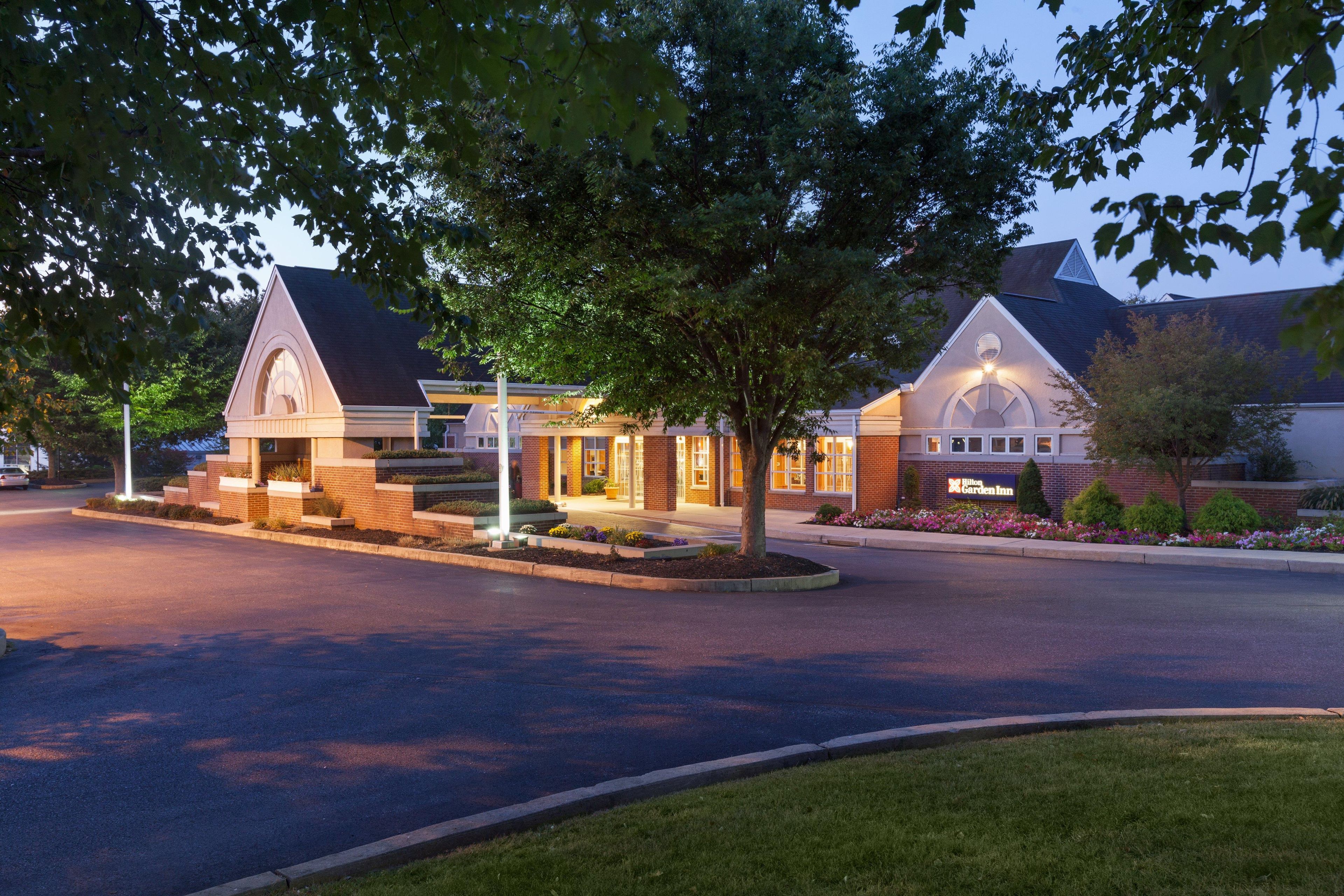 A hotel with a brick facade, a large entrance, and a well-lit driveway.