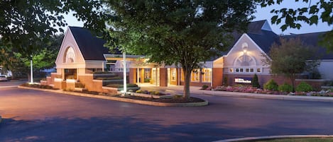 A hotel with a brick facade, a large entrance, and a well-lit driveway.