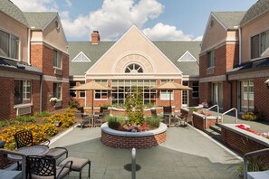A courtyard with a central seating area, surrounded by brick buildings with large windows and a triangular roof structure. - Hilton Garden Inn Lancaster (Lancaster)