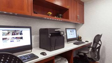 Un espace de travail équipé de deux ordinateurs de bureau, d’une imprimante et d’une chaise.