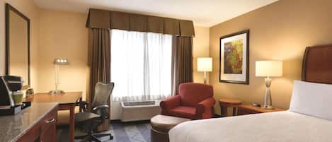 Une chambre d’hôtel équipée d’un lit, d’un bureau, d’une chaise, d’un climatiseur et d’une fenêtre avec des rideaux.