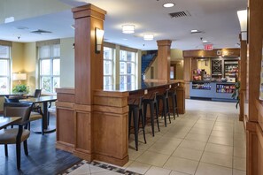 A hotel lobby with a bar area, seating, and a staircase.