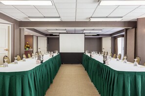 A conference room with a long table, chairs, a projector screen, and a carpeted floor.