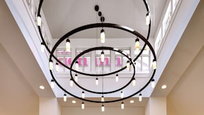 A spacious lobby with a modern chandelier, a reception desk, and a coffee shop area.