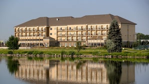 A multi-story hotel with balconies, a reflection pool, and a well-maintained lawn.