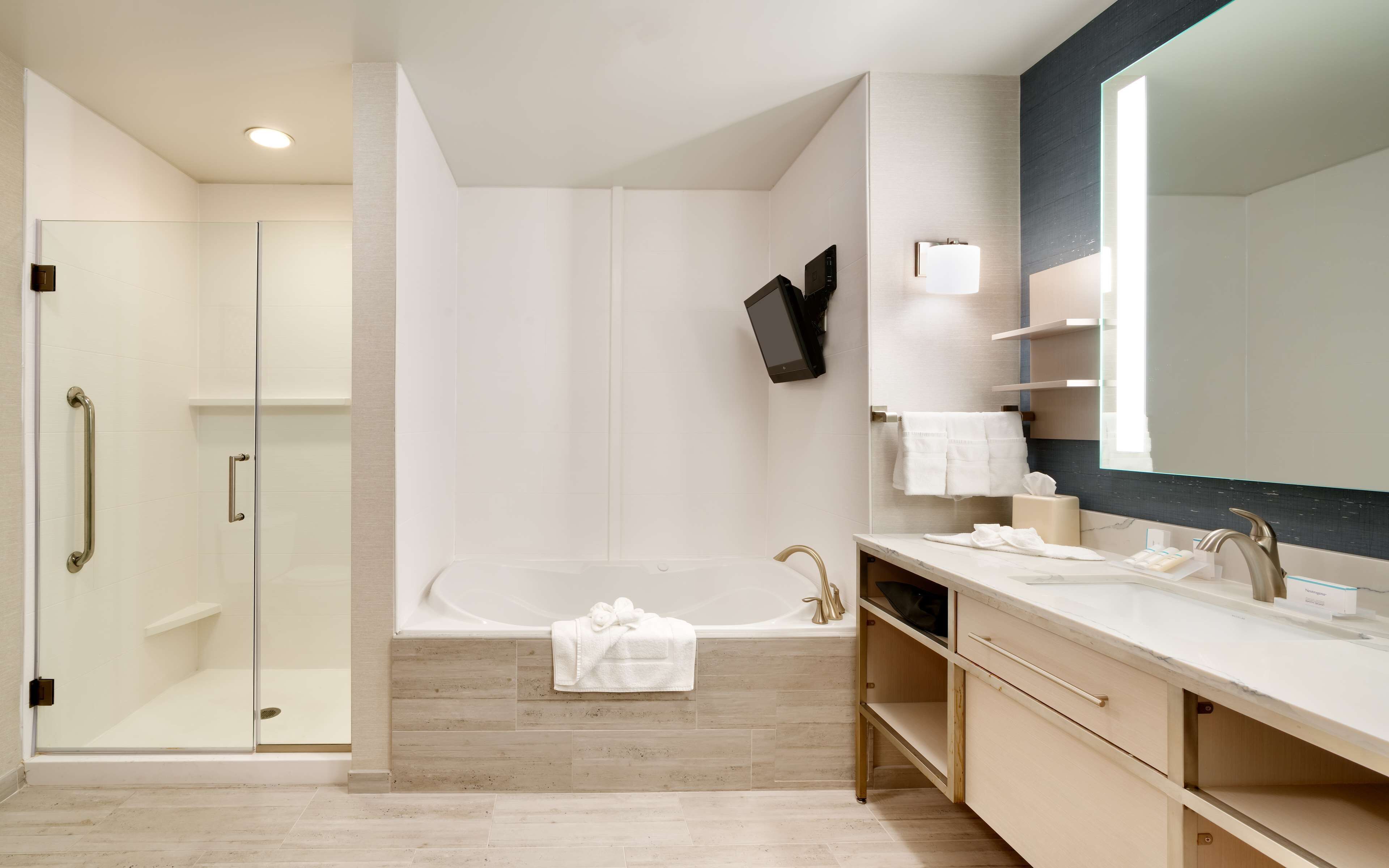 Un baño moderno con cabina de ducha de vidrio, una bañera independiente y un espejo grande.