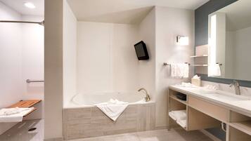 A modern bathroom with a bathtub, a large mirror, a vanity with a sink, and a shower area.