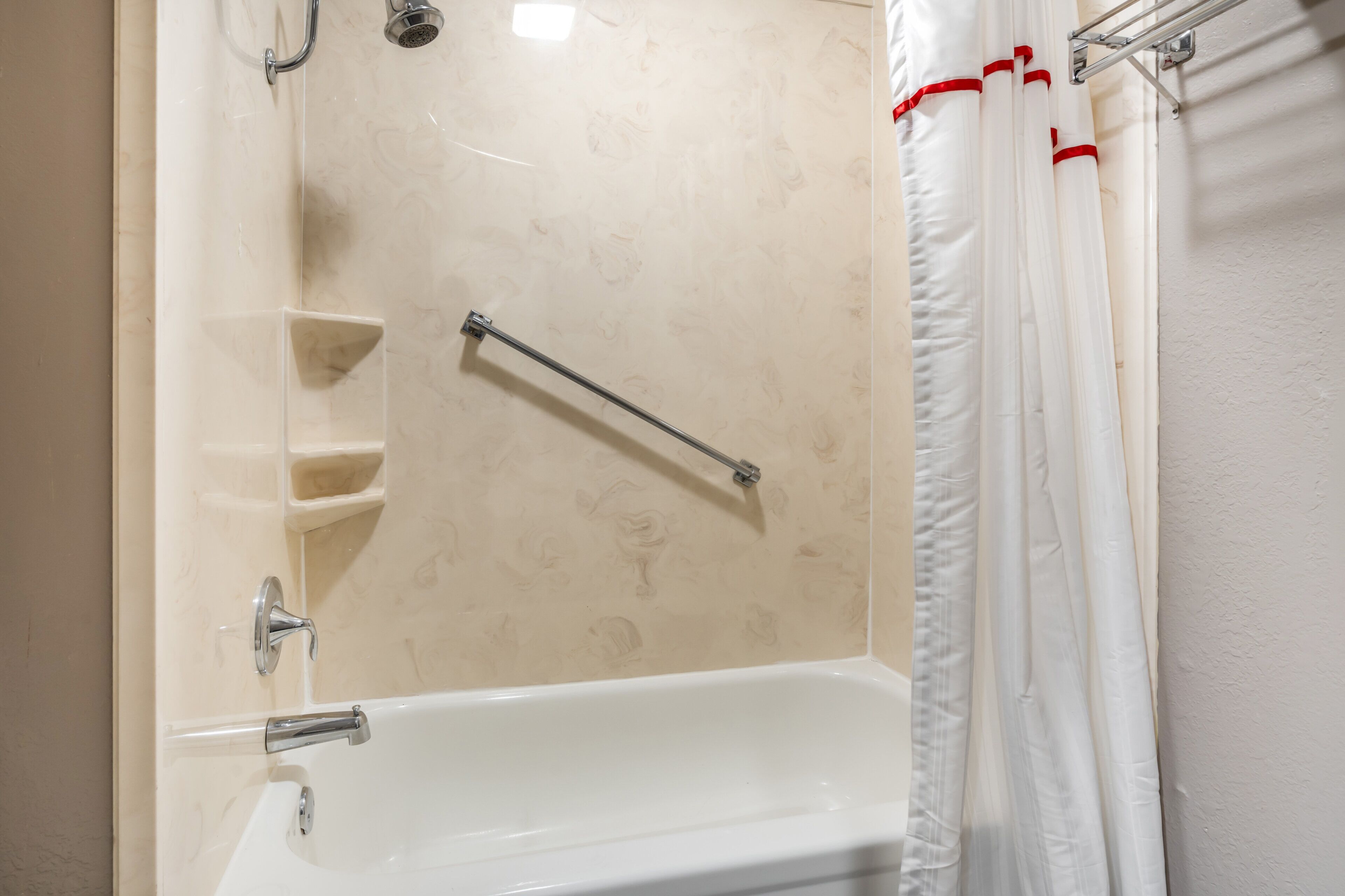 Un baño con bañera, barra de apoyo y cortina de ducha.