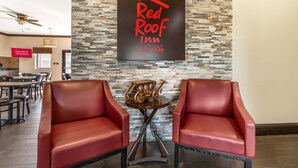 Ein Red Roof Inn Schild an einer Steinmauer, zwei rote Ledersessel und ein Tisch mit einem Modell eines Oldtimers.