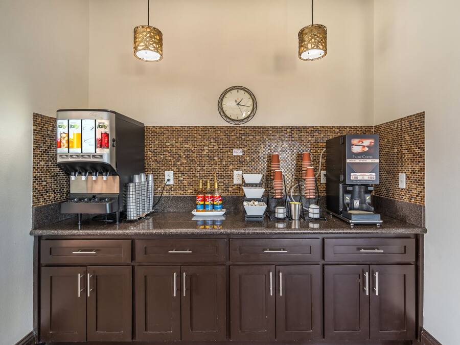 A coffee station with a coffee machine, a water dispenser, and a clock on the wall.