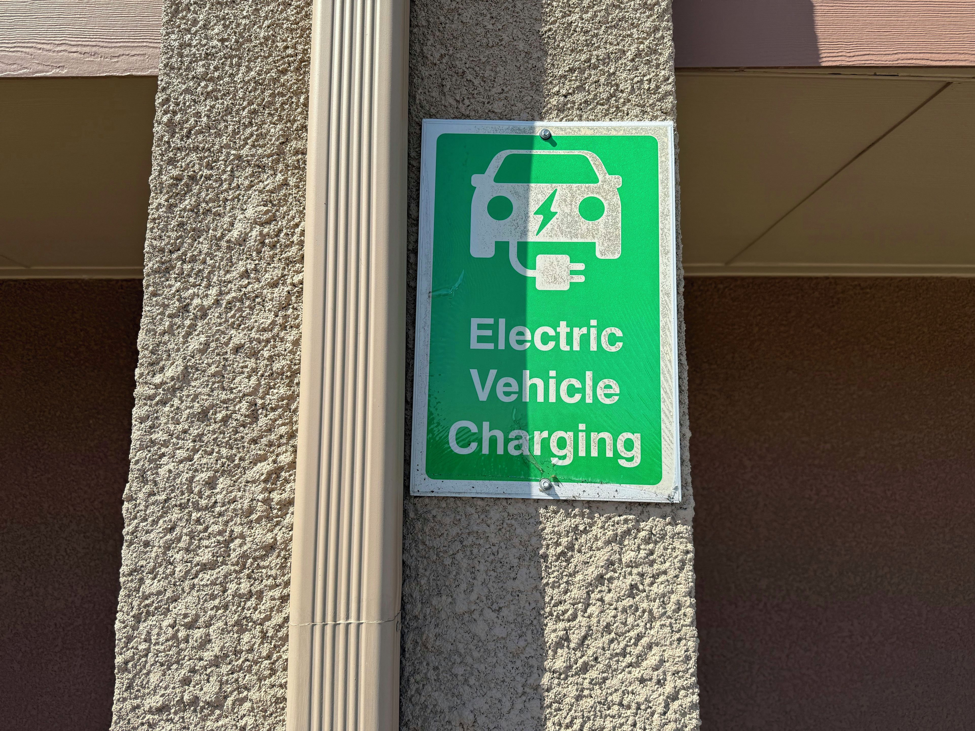 A sign for electric vehicle charging on a textured wall.