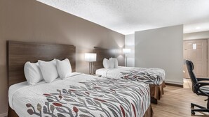 Ein Hotelzimmer mit zwei Betten, einem Schreibtisch und einem Stuhl.