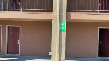 A building with a two-story balcony, a green sign indicating electric vehicle charging, and two doors with numbers 304 and 305.